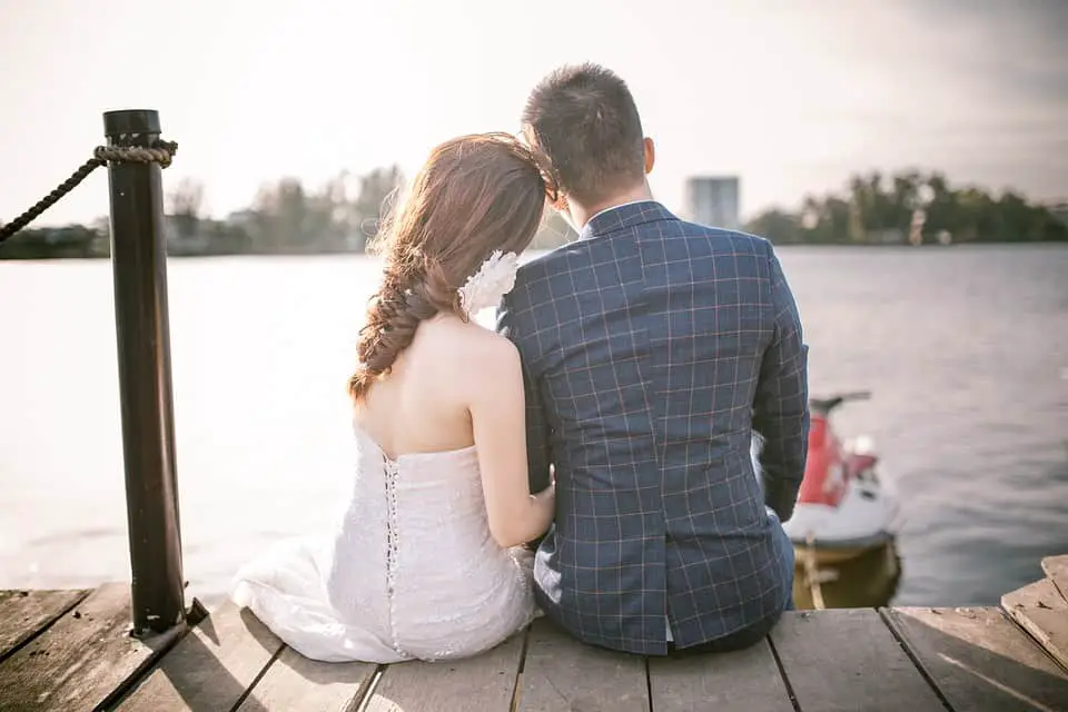 wedding couple sitting by the lake