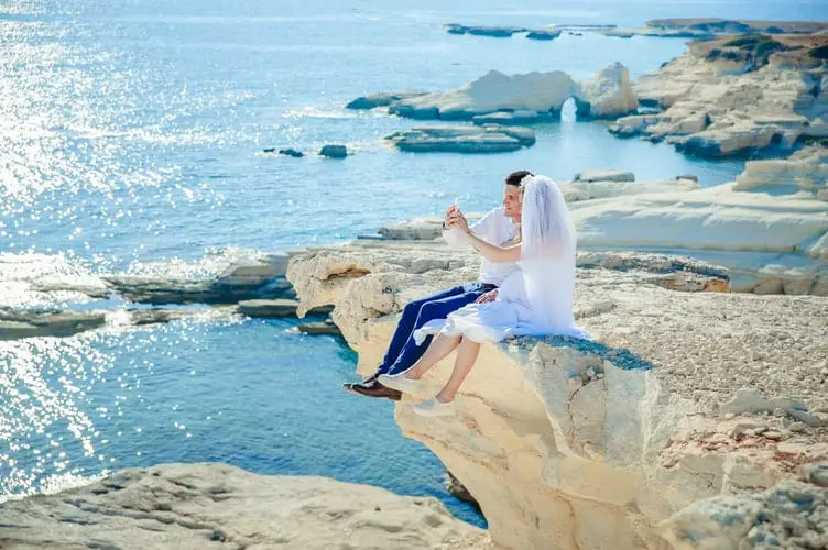 bride and groom sitting over a cliff