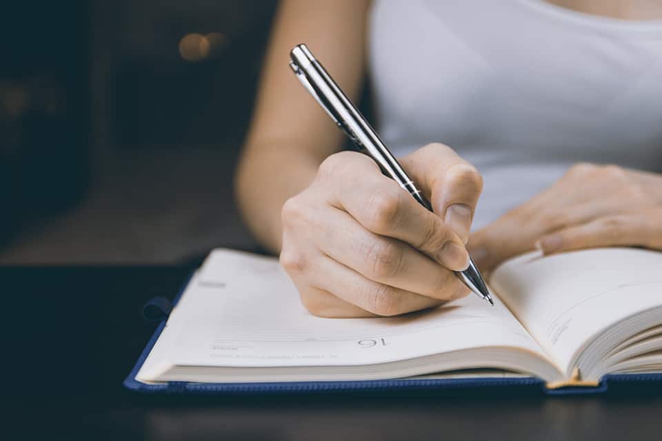 person writing on notebook