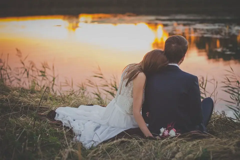 bride and groom sitting by the lake