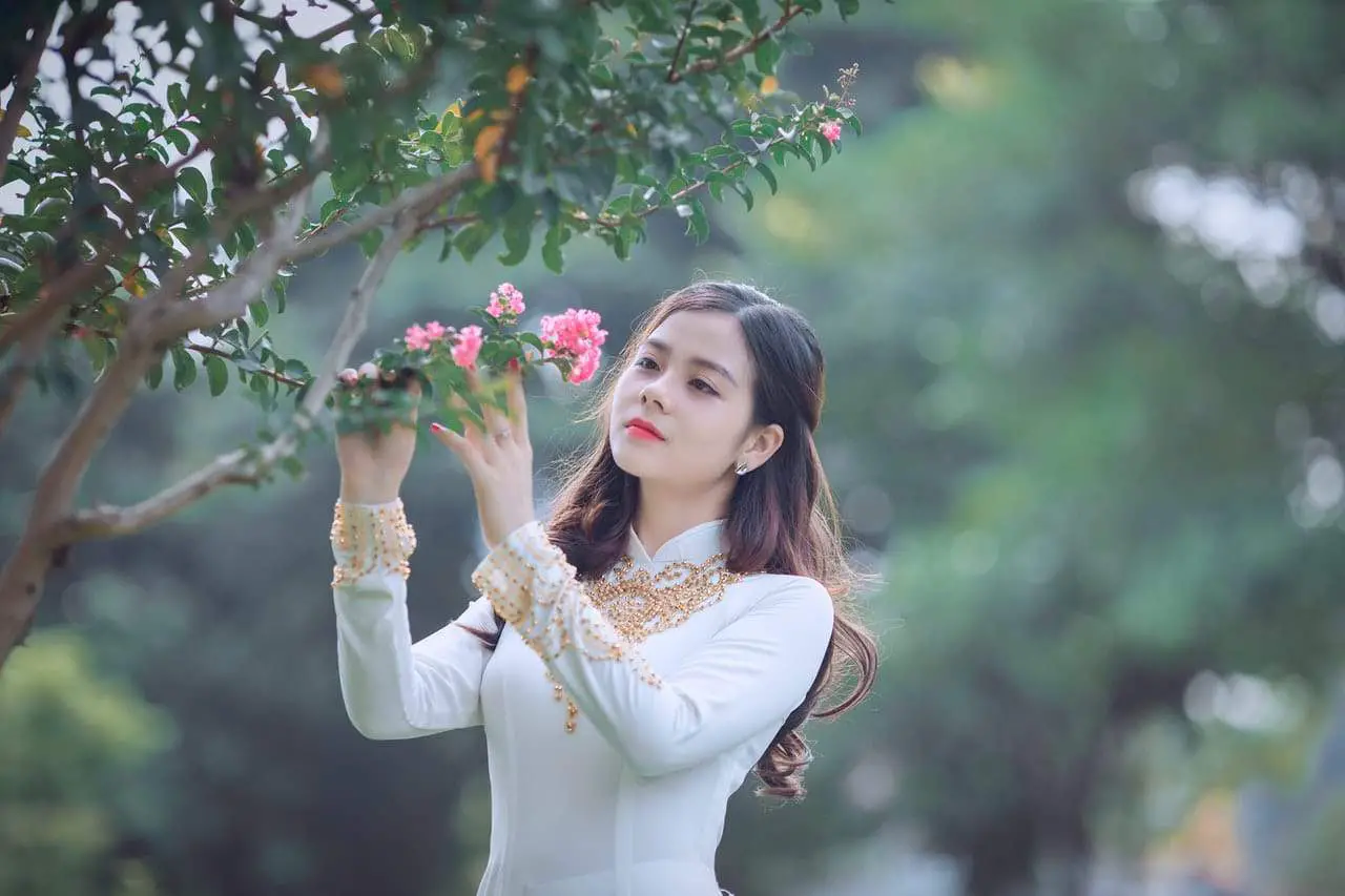 Woman in wihte dress picking a flower