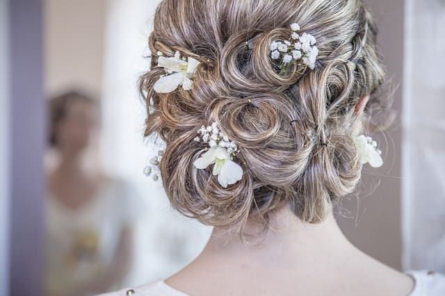 a bride with trendy bridal bun fixed by her hairstylist, one of the wedding 