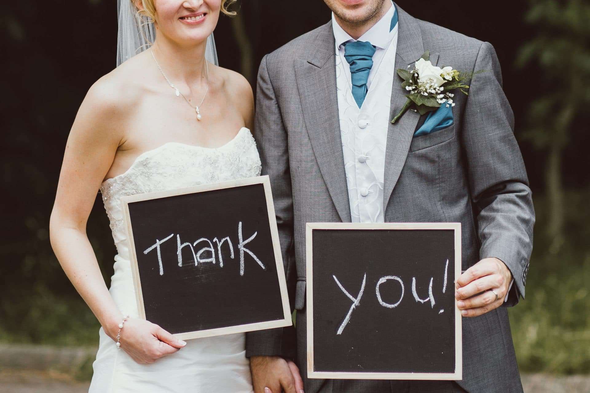 bride and groom holding chalk boards in which the words thank you! are written