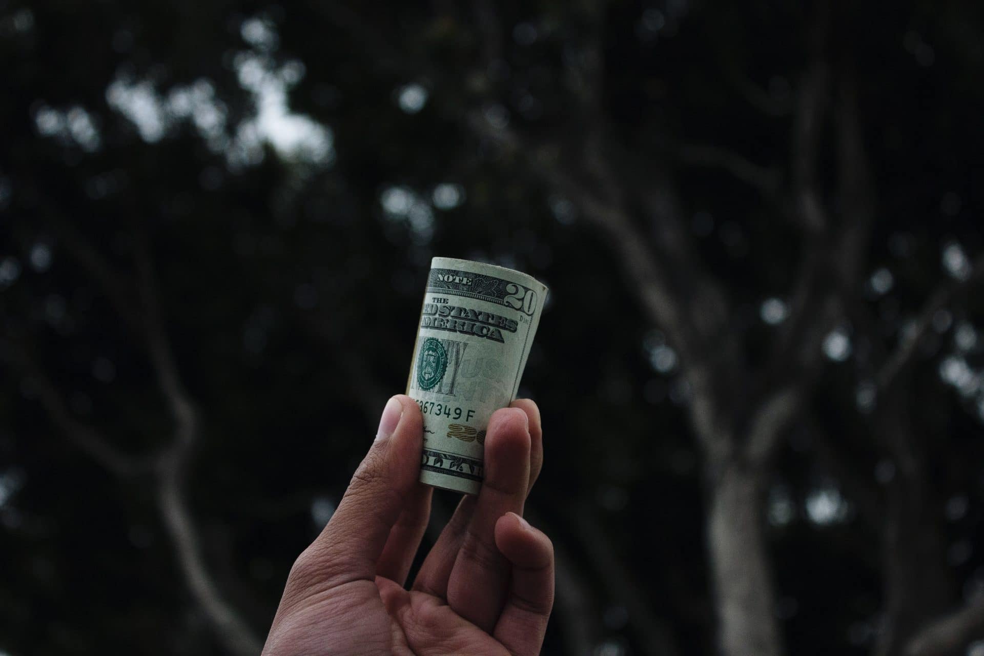 a person holding rolled dollar bills and wondering how much to tip wedding vendors