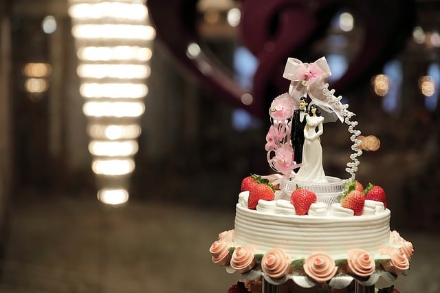 a perfect wedding cake with couple figurine and fresh strawberries